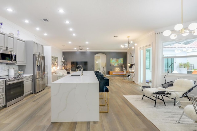 kitchen featuring ornamental molding, stainless steel appliances, decorative light fixtures, and a kitchen breakfast bar