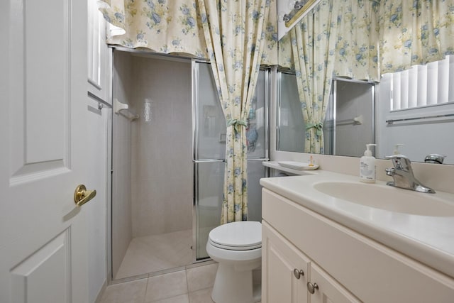 bathroom featuring tile patterned floors, toilet, a shower with door, and vanity