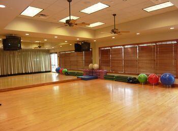 workout area featuring ceiling fan, wood-type flooring, and a raised ceiling