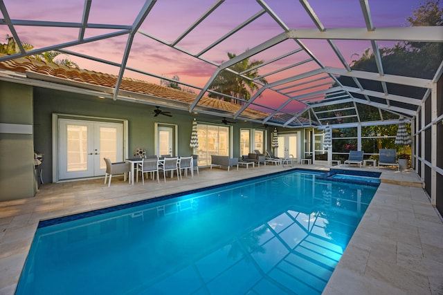 pool at dusk featuring a lanai, ceiling fan, a patio area, an outdoor hangout area, and french doors