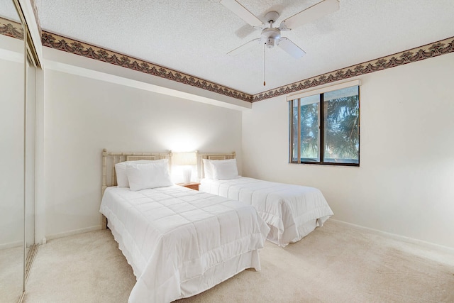 carpeted bedroom with ceiling fan and a textured ceiling