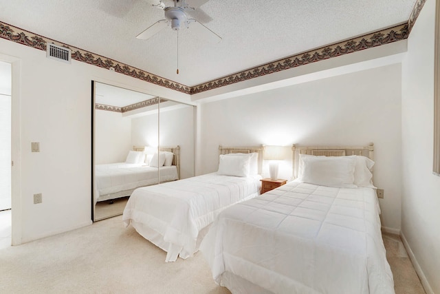 carpeted bedroom featuring ceiling fan and a textured ceiling