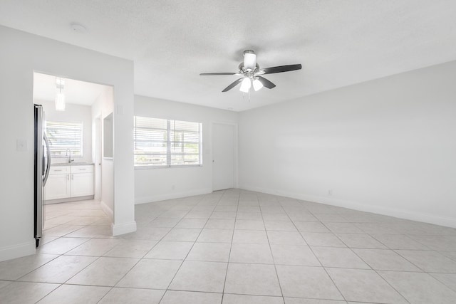 spare room featuring light tile patterned flooring, ceiling fan, and a healthy amount of sunlight