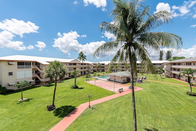 view of community featuring tennis court and a lawn