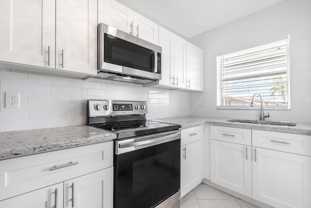 kitchen featuring white cabinets, appliances with stainless steel finishes, light stone countertops, and sink