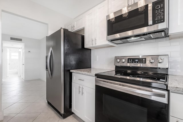 kitchen featuring light stone countertops, appliances with stainless steel finishes, decorative backsplash, and white cabinetry