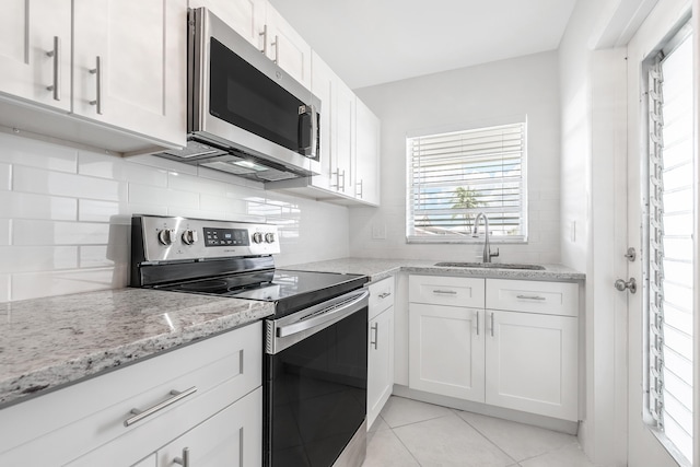 kitchen featuring stainless steel appliances, white cabinets, sink, and light stone countertops