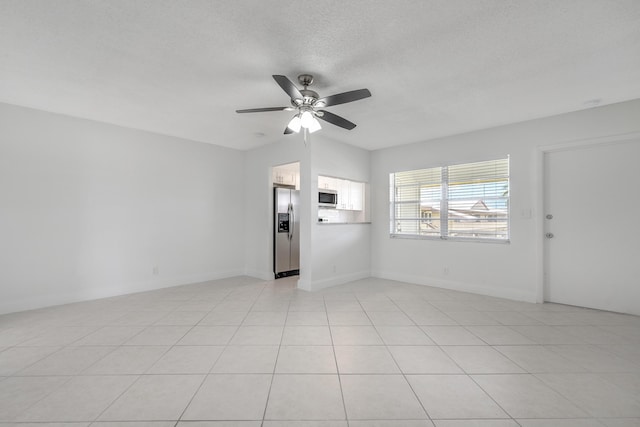 empty room with ceiling fan, a textured ceiling, and light tile patterned floors