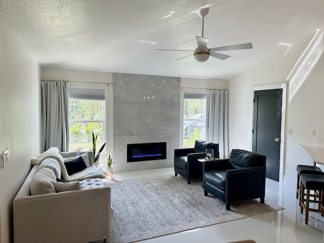 living room featuring a textured ceiling, a fireplace, ceiling fan, and a wealth of natural light