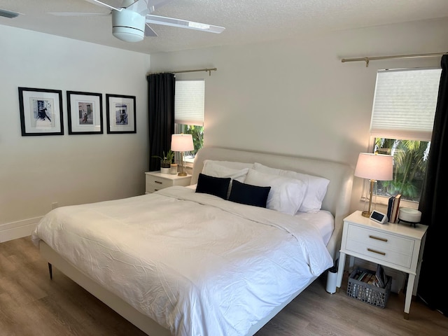 bedroom with a textured ceiling, ceiling fan, and dark hardwood / wood-style floors