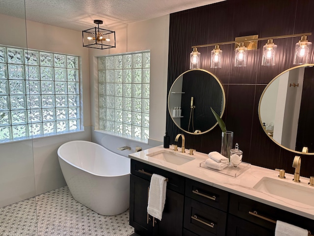 bathroom featuring vanity, a textured ceiling, a bathtub, and a notable chandelier