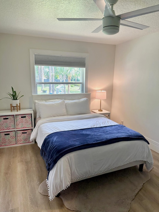 bedroom featuring ceiling fan, light wood-type flooring, and a textured ceiling