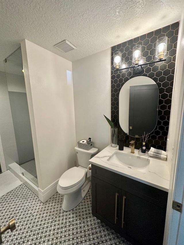 bathroom with toilet, vanity, a textured ceiling, and walk in shower