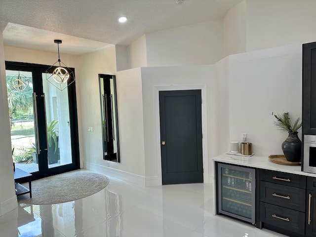 foyer with beverage cooler and a textured ceiling