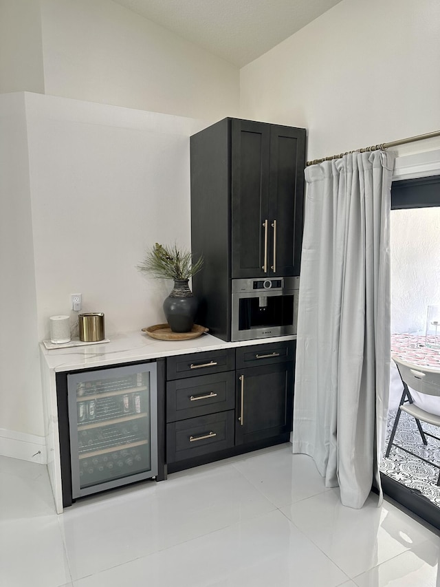 bar with stainless steel oven, light tile patterned floors, and wine cooler