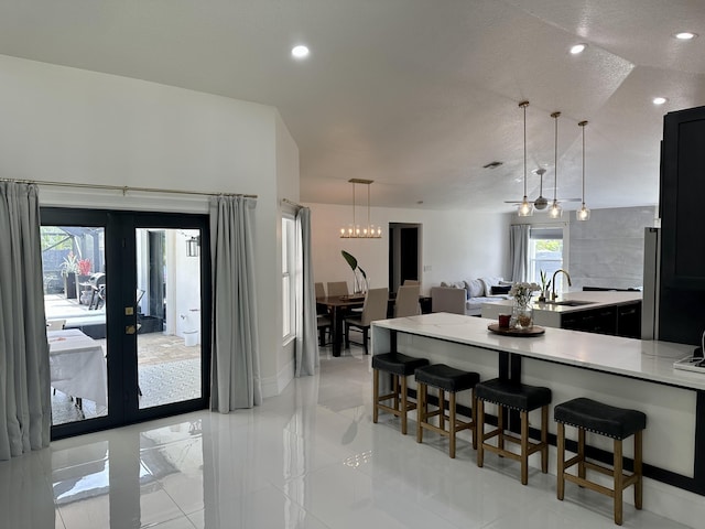 kitchen with vaulted ceiling, pendant lighting, french doors, a kitchen bar, and sink