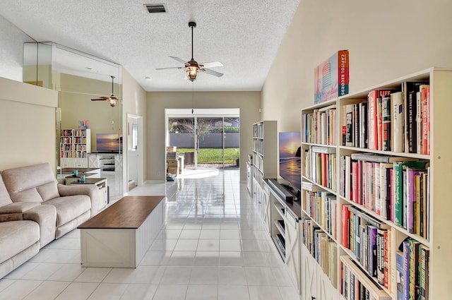 living room with ceiling fan, a textured ceiling, and light tile patterned floors