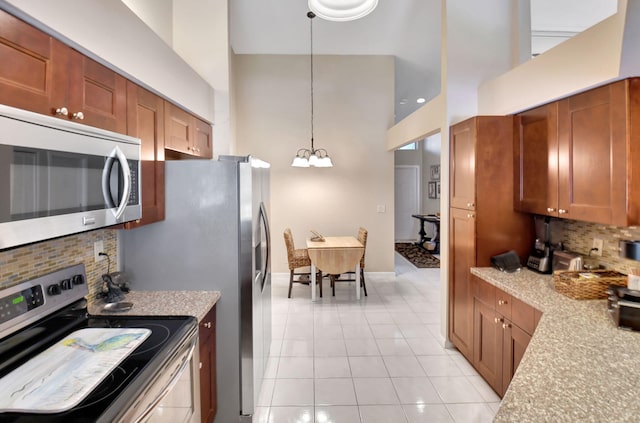 kitchen featuring tasteful backsplash, decorative light fixtures, appliances with stainless steel finishes, a notable chandelier, and a towering ceiling