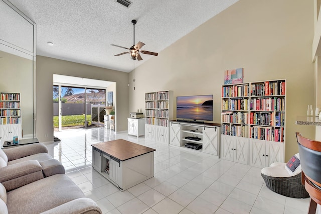 living room featuring ceiling fan, high vaulted ceiling, a textured ceiling, and light tile patterned floors