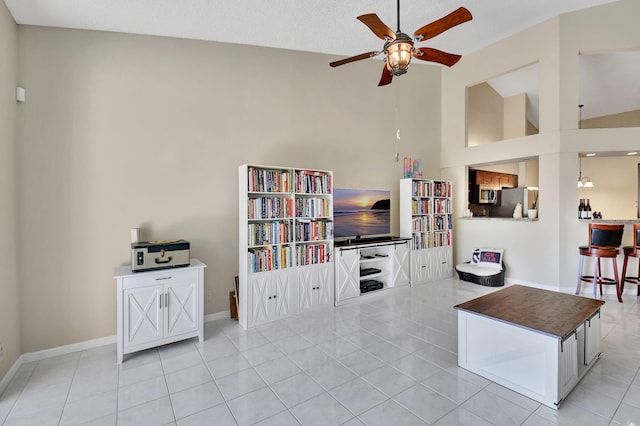 tiled living room with ceiling fan, high vaulted ceiling, and a textured ceiling