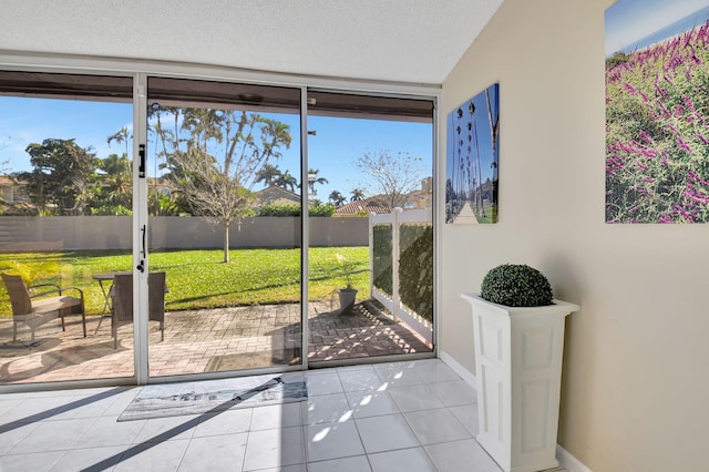 doorway to outside featuring a wealth of natural light, floor to ceiling windows, a textured ceiling, and light tile patterned flooring