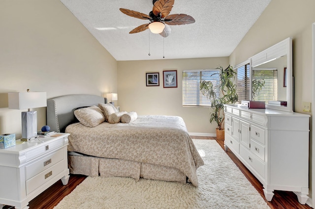 bedroom with lofted ceiling, a textured ceiling, dark hardwood / wood-style floors, and ceiling fan