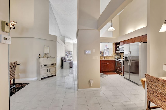 kitchen featuring stainless steel appliances, tasteful backsplash, a towering ceiling, and pendant lighting