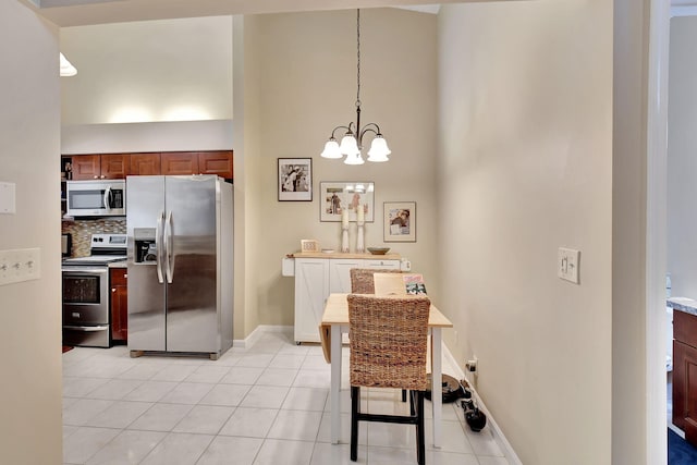 kitchen with stainless steel appliances, light tile patterned flooring, hanging light fixtures, and a high ceiling