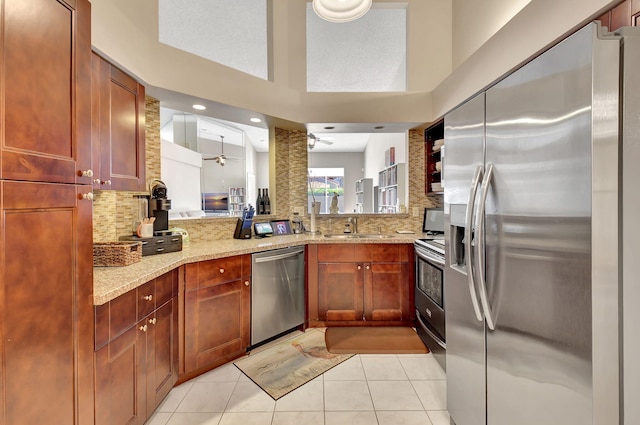 kitchen with sink, light tile patterned floors, stainless steel appliances, light stone countertops, and backsplash