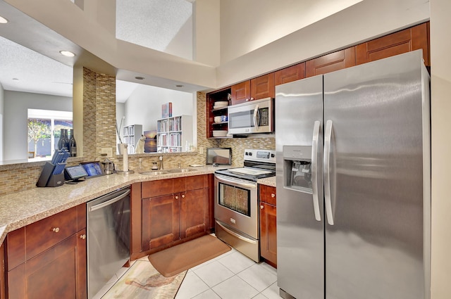 kitchen featuring sink, appliances with stainless steel finishes, backsplash, light stone counters, and light tile patterned flooring