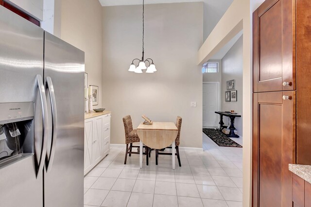 tiled dining space featuring an inviting chandelier and a towering ceiling