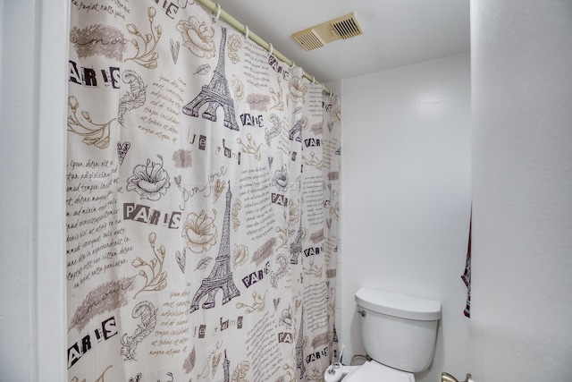 bathroom featuring toilet and curtained shower