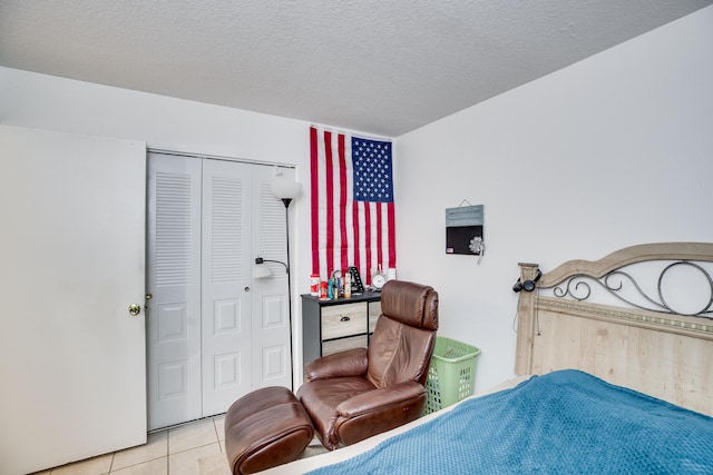 tiled bedroom with a textured ceiling and a closet