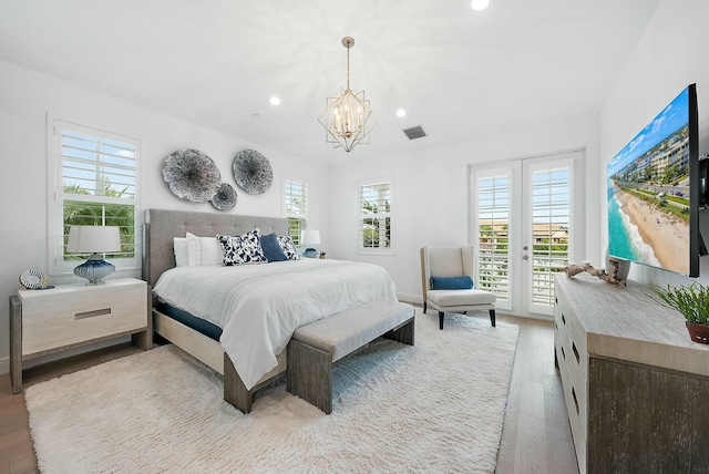 bedroom with an inviting chandelier, light hardwood / wood-style floors, and access to exterior