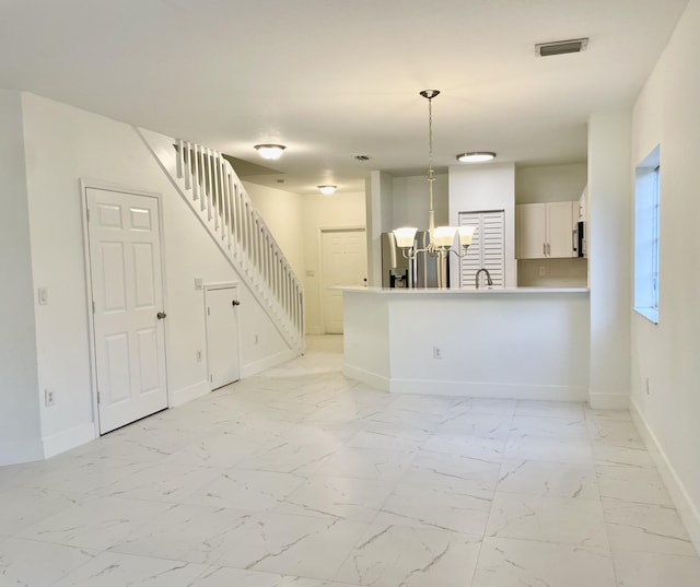 interior space with white cabinets, kitchen peninsula, a chandelier, and pendant lighting