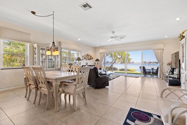 tiled dining space with ceiling fan with notable chandelier and a textured ceiling