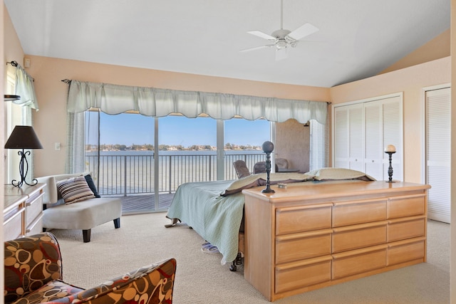 bedroom featuring multiple windows, access to exterior, light colored carpet, and a water view