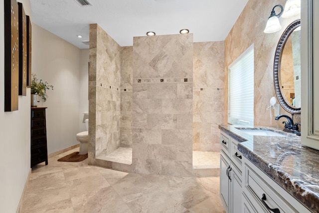 bathroom with vanity, toilet, and a tile shower