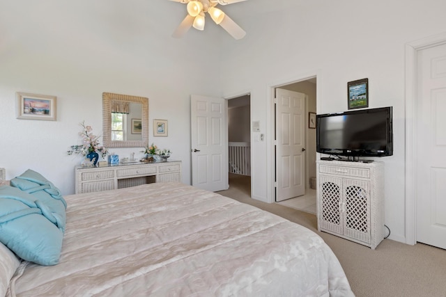 bedroom featuring a towering ceiling, light colored carpet, and ceiling fan