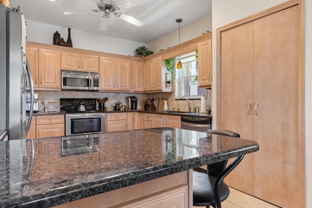 kitchen with a breakfast bar, dark stone countertops, stainless steel appliances, decorative backsplash, and decorative light fixtures