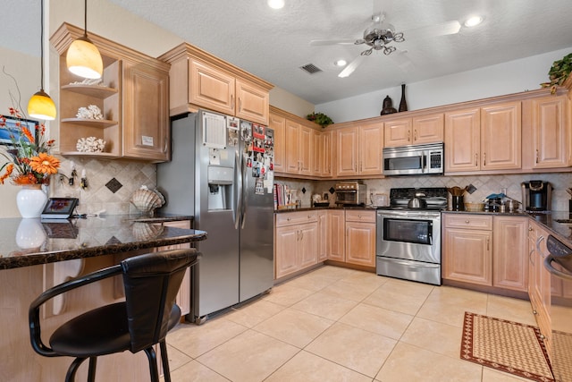 kitchen featuring decorative light fixtures, tasteful backsplash, light tile patterned floors, stainless steel appliances, and light brown cabinets