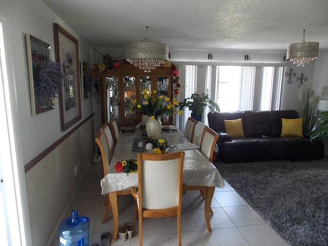 dining space featuring light tile patterned flooring, a chandelier, and a textured ceiling