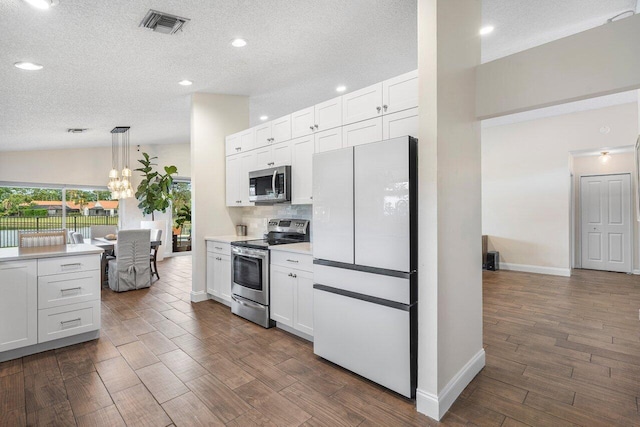 kitchen featuring white cabinets, appliances with stainless steel finishes, vaulted ceiling, and pendant lighting