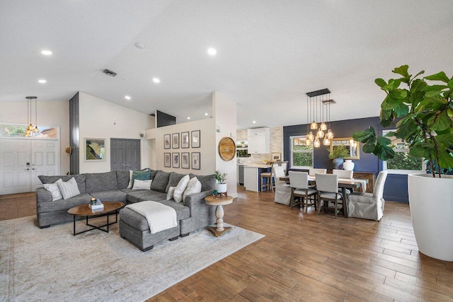 living room featuring a textured ceiling, a chandelier, and vaulted ceiling