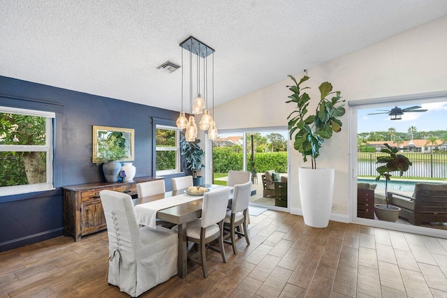 dining space with a textured ceiling and vaulted ceiling