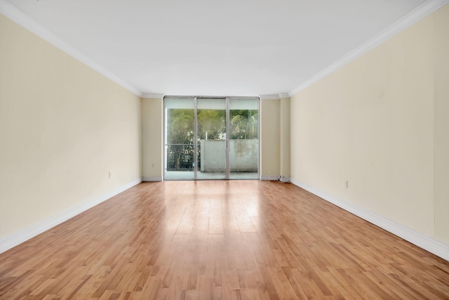 spare room featuring light hardwood / wood-style floors, crown molding, and expansive windows