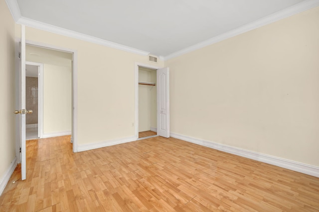 unfurnished bedroom with a closet, light hardwood / wood-style floors, and crown molding