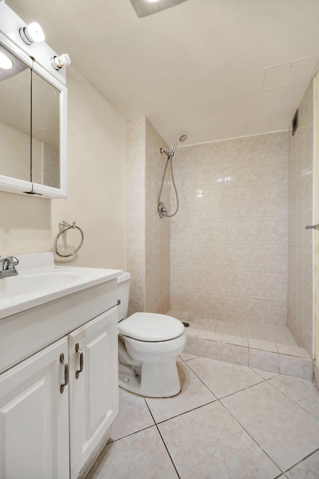 bathroom featuring toilet, tile patterned flooring, vanity, and tiled shower