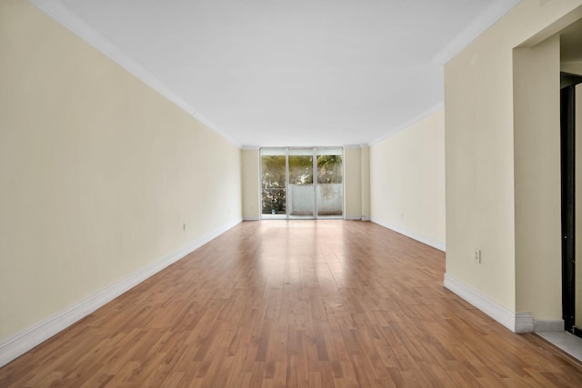 spare room with a wall of windows, crown molding, and light hardwood / wood-style flooring