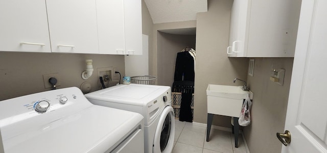 clothes washing area featuring cabinet space, washing machine and clothes dryer, a sink, baseboards, and light tile patterned flooring